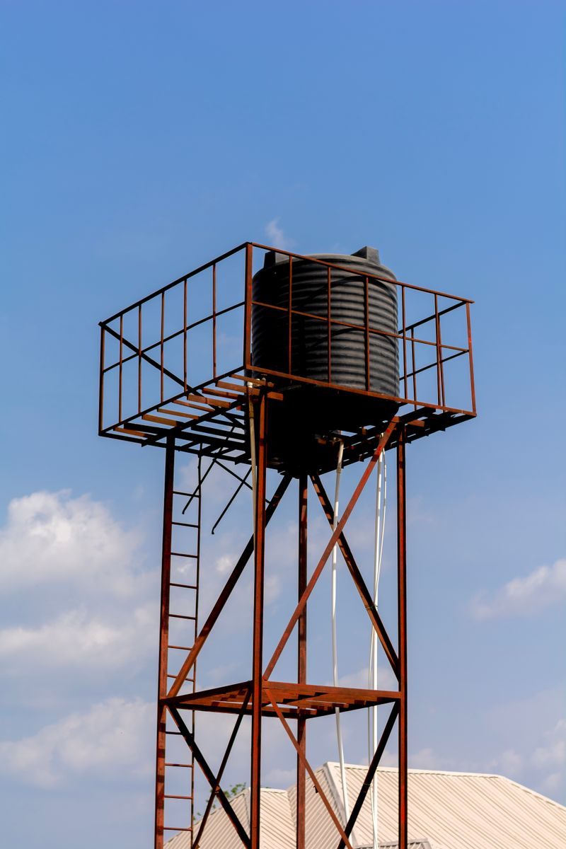 High metal water tower structure against a clear blue sky in Ado Ekiti, Nigeria.